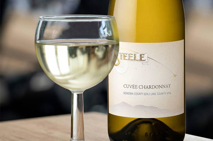 Bottle of Steele Chardonnay wine on a table with a perfectly shaped wine glass.